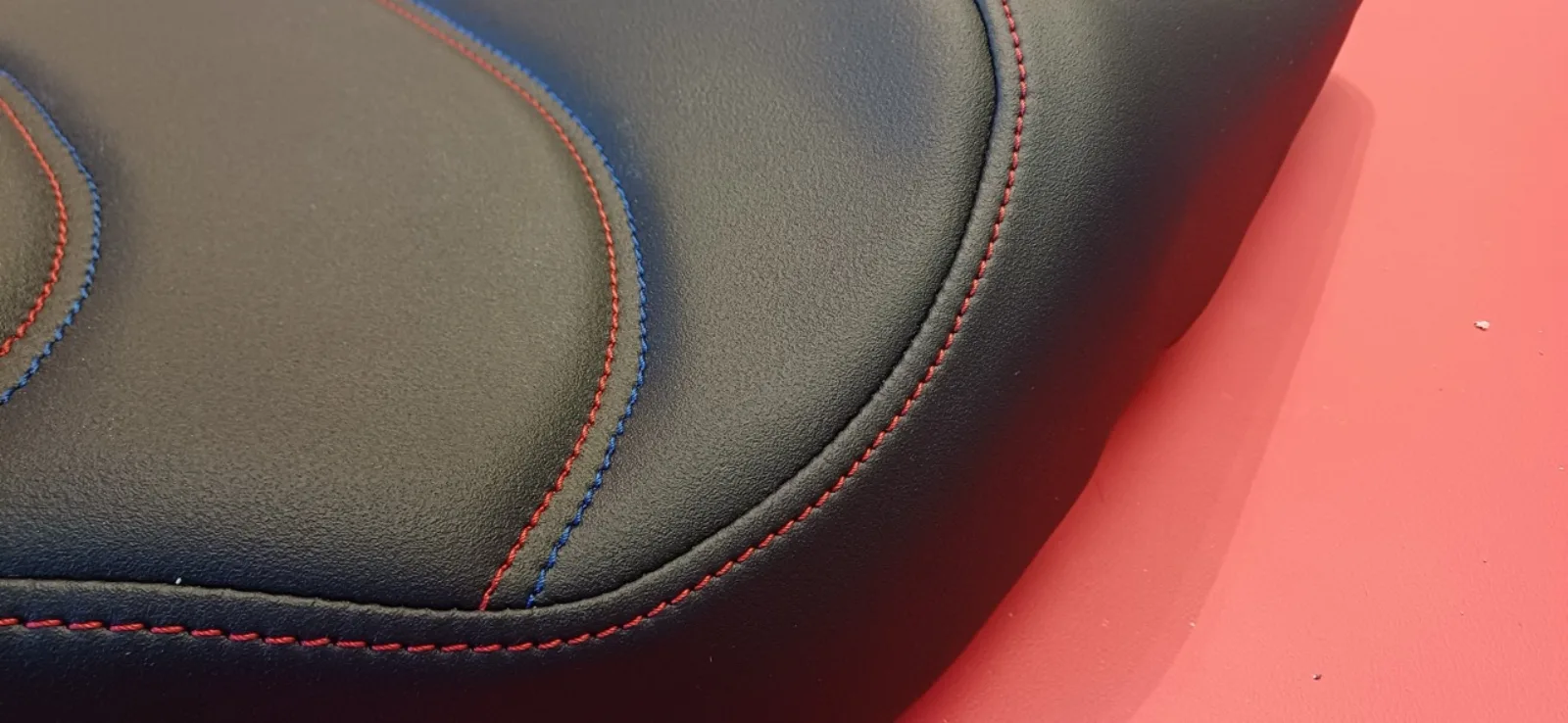Selle de moto noire avec surpiqûres rouges et bleues